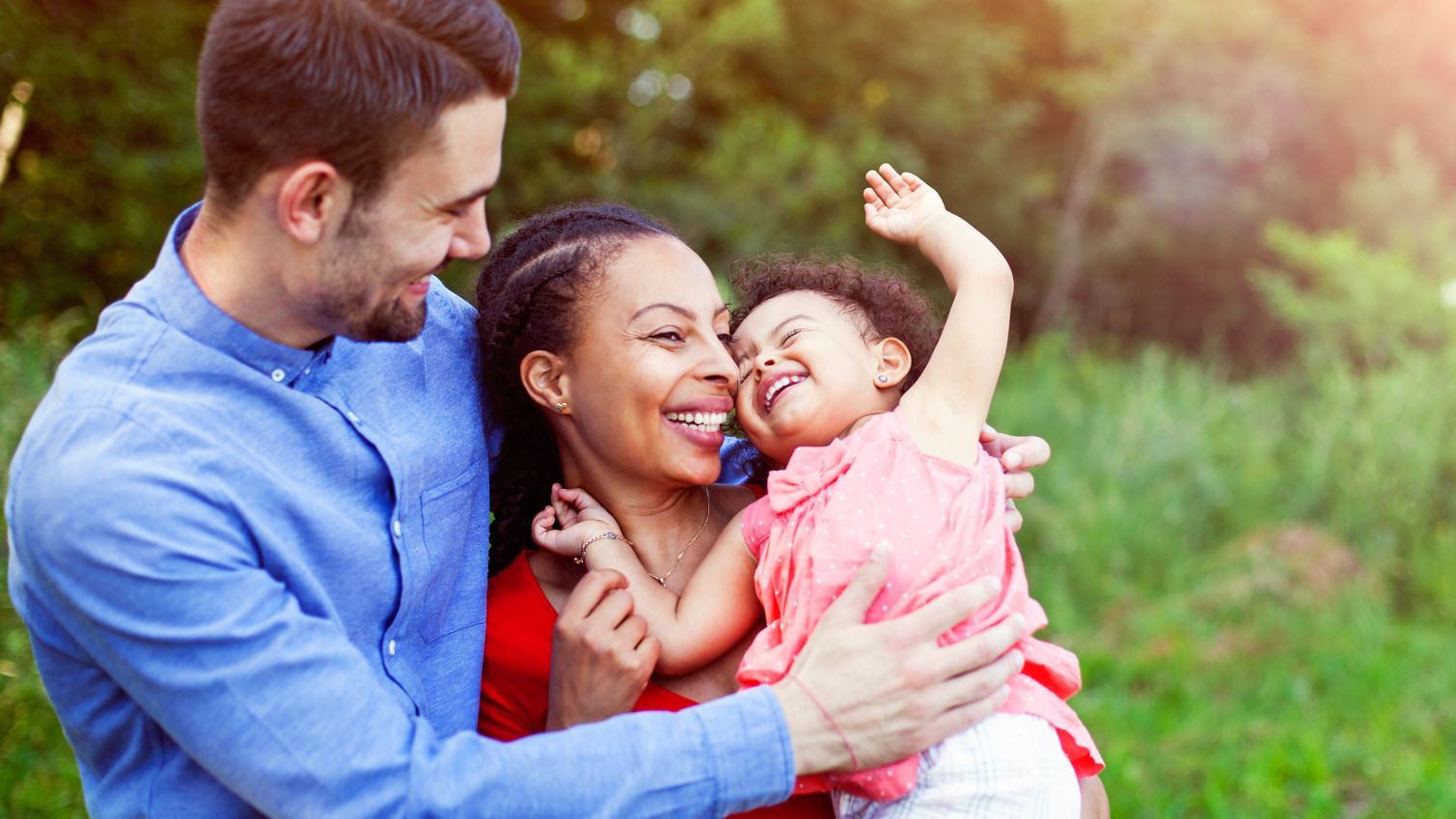 Parents playfully hold their child outside